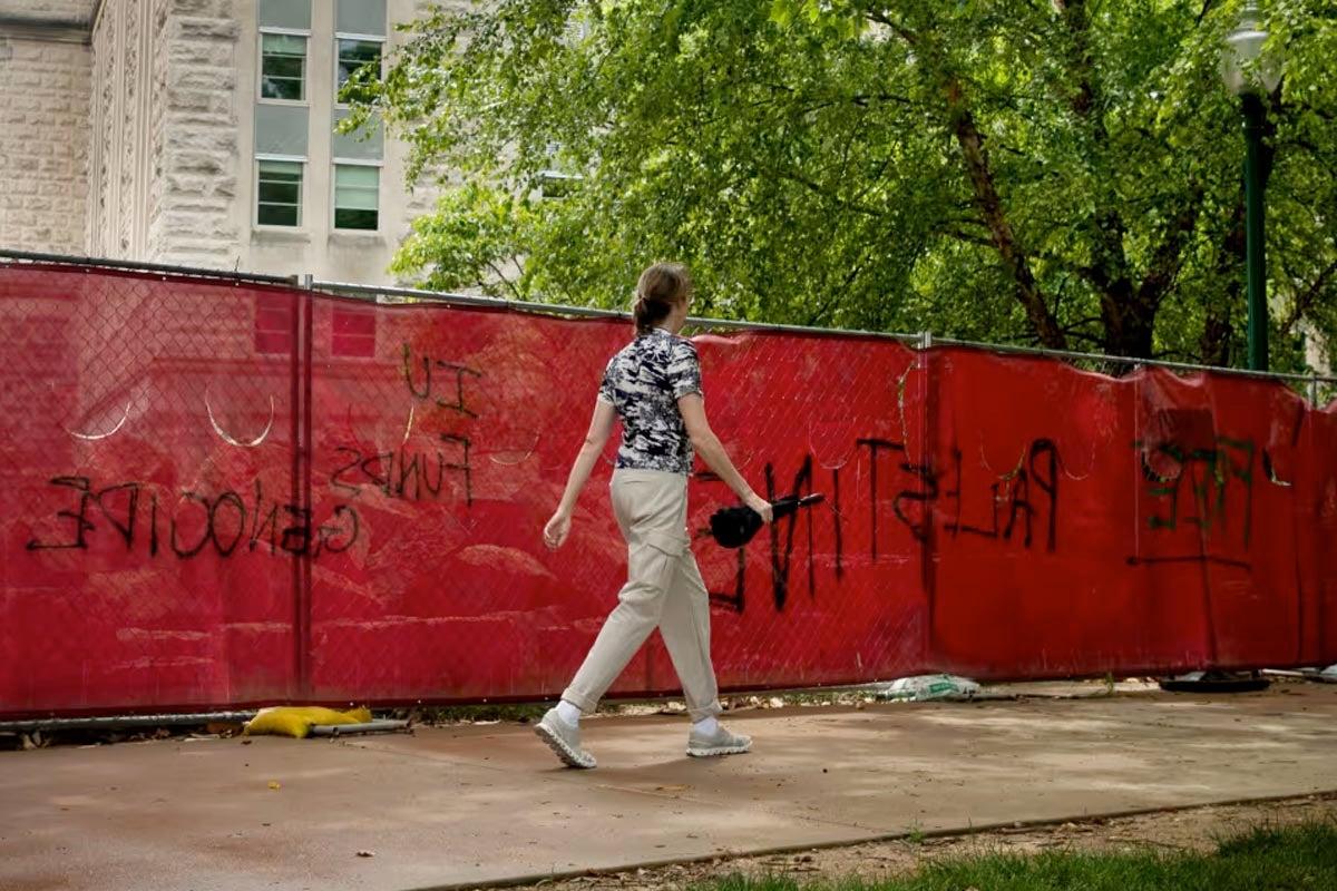 pedestrian walking with umbrella next to Free Palestine graffiti